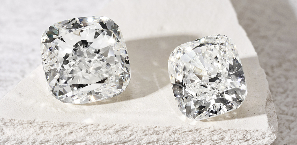 Two different sized cushion cut diamonds sparkling on a gravel stone top. 