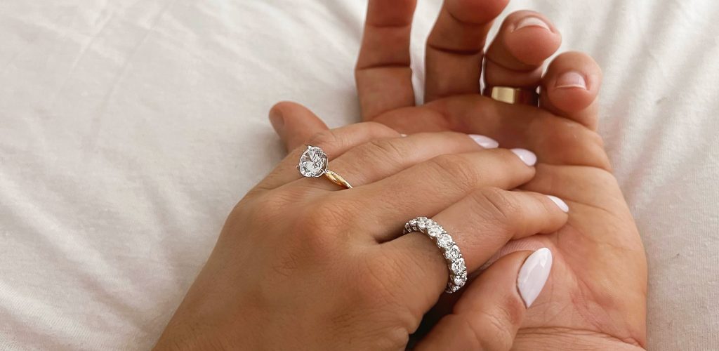 A couple holding hands while wearing diamond and plain gold promise rings 