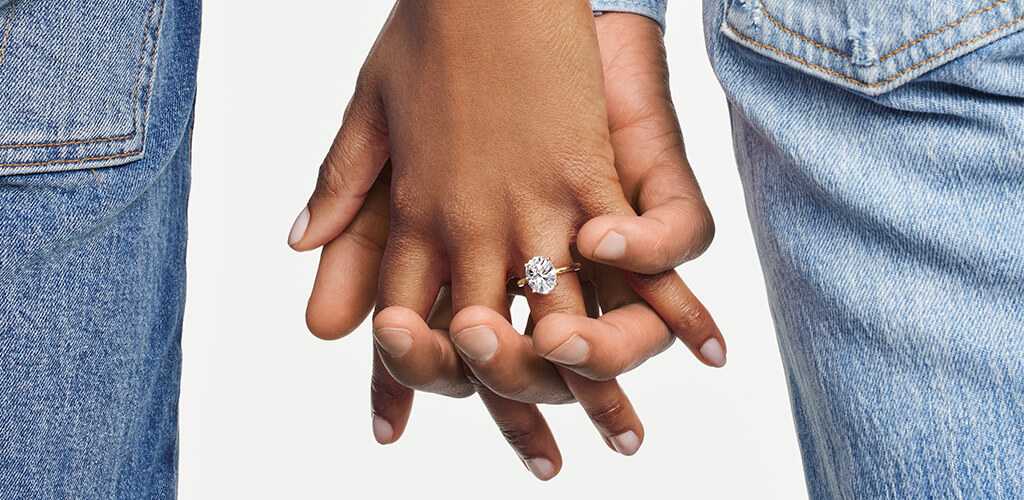 A couple holding hands- she is wearing a large engagement ring 