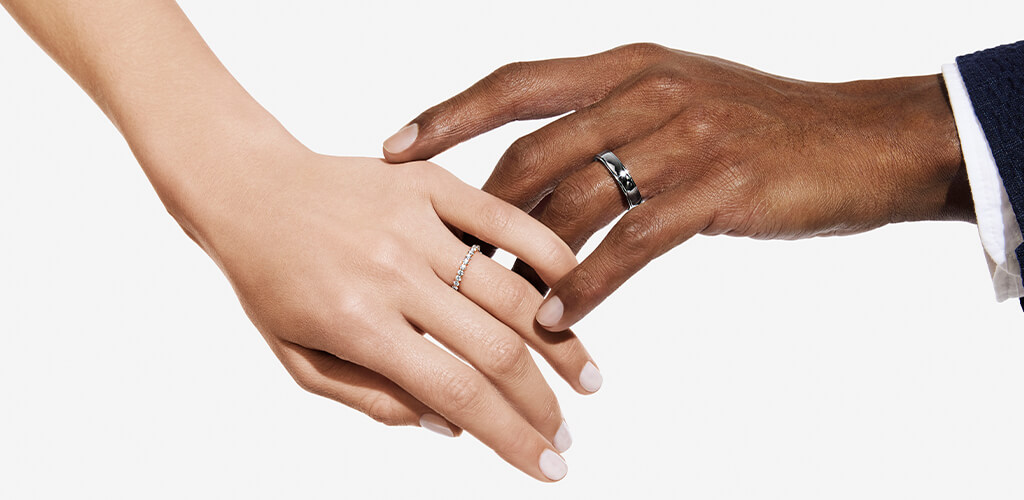 A couple touching hands while showing off their wedding rings 