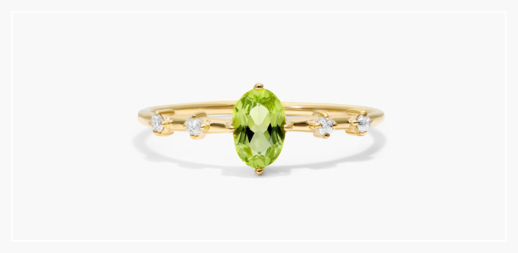 Gold peridot ring and necklace set on a display platform, showing bright green August birthstone jewelry styling.
