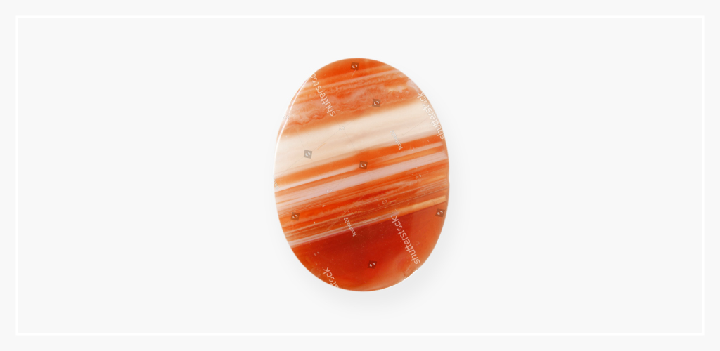 An alternative August birthstone, this orange and white sardonyx stone sits upright on a table.