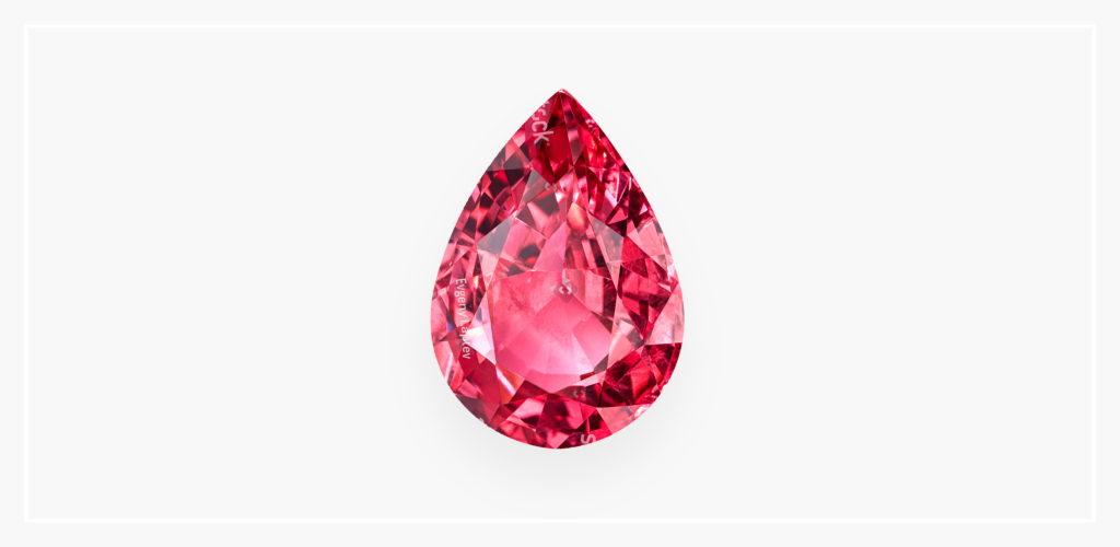 Pear-shaped pink spinel gemstone against a white backdrop. This August birthstone is featured with a faceted cut.