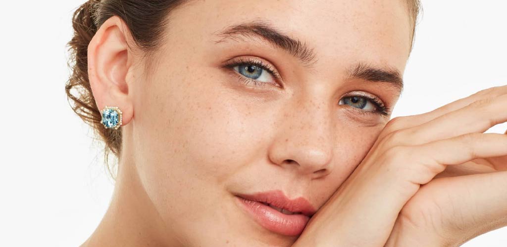 A model wearing a pair of blue topaz earrings