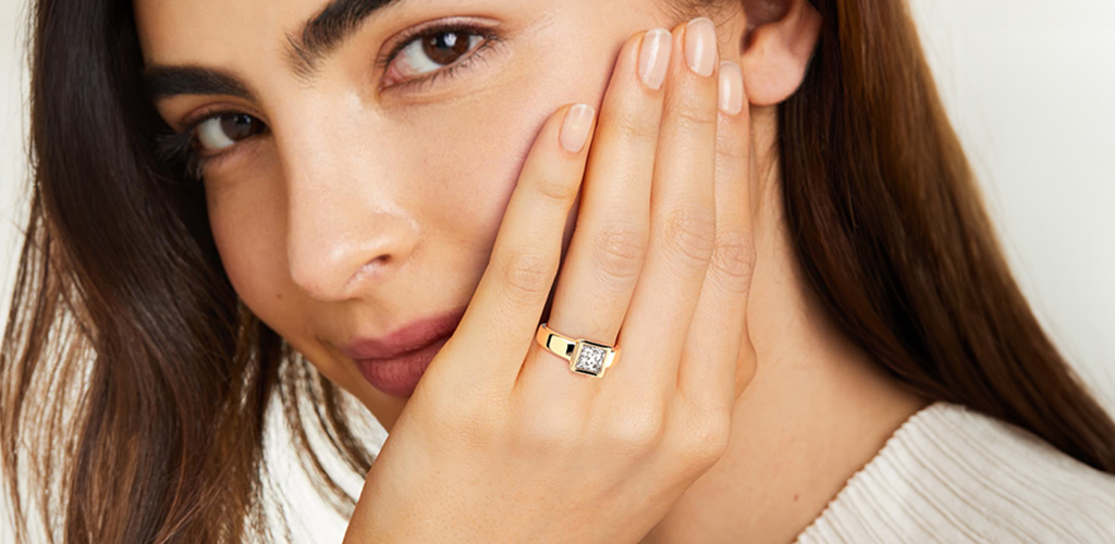Woman showing a bold square-cut gold ring that sits close to the hand, a style often chosen for engagement rings for active lifestyles