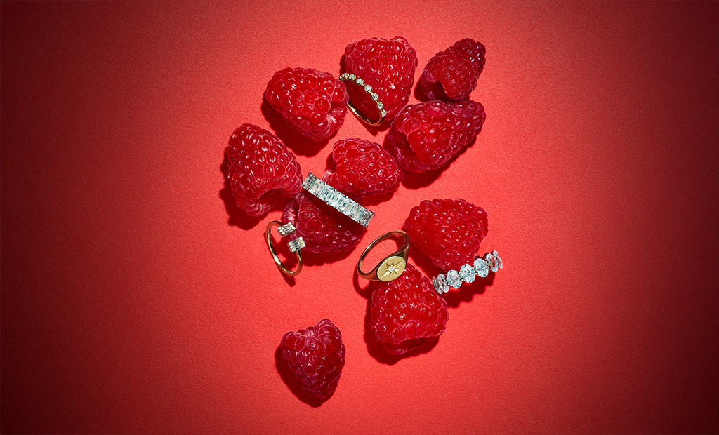 Diamond rings from the new James Allen Valentine’s Day collection arranged with red raspberries on a red background.